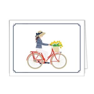 folded notecard in white with a blue border, front of notecard has a girl in white pants and a blue and white striped shirt wearing a resort straw hat on a red bike with yellow tulips in a wicker bike basket