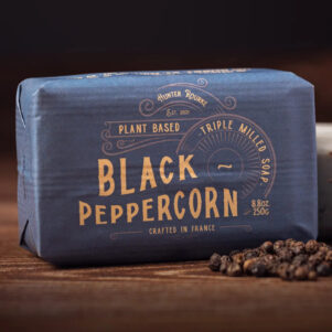 french soap bar wrapped in black paper with gold writing. black peppercorn scent with crushed black peppercorns for exfoliation